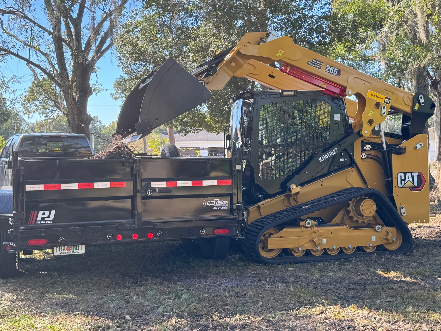 Track loader loading debris into a dump trailer
